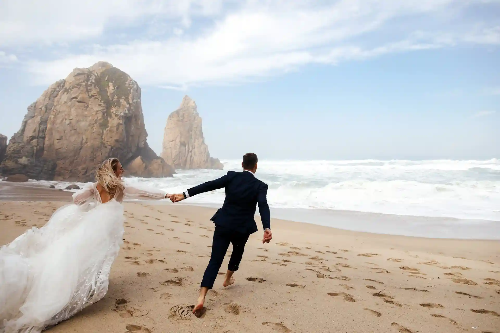 Glückliches Brautpaar läuft am Strand baarfuss